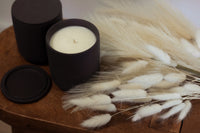 Unlit black matte candles styled with white dried florals on a wooden surface